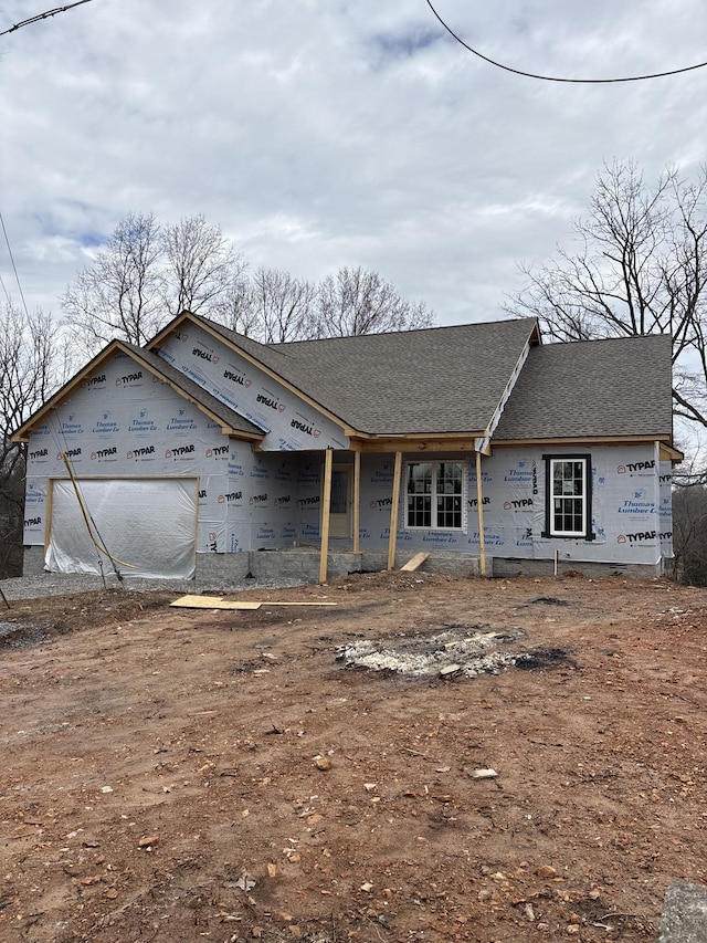 unfinished property with a garage and a shingled roof