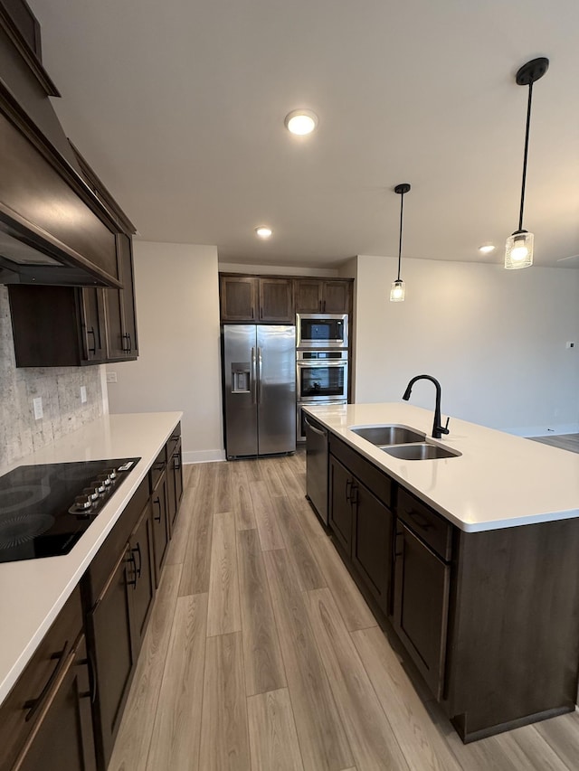 kitchen with tasteful backsplash, sink, hanging light fixtures, light hardwood / wood-style floors, and stainless steel appliances