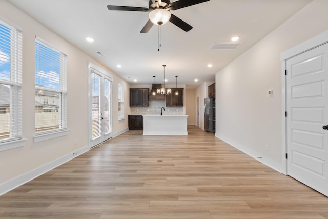 unfurnished living room featuring ceiling fan, sink, and light hardwood / wood-style floors