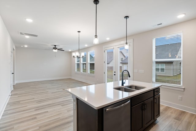 kitchen featuring sink, light hardwood / wood-style floors, stainless steel dishwasher, hanging light fixtures, and a kitchen island with sink