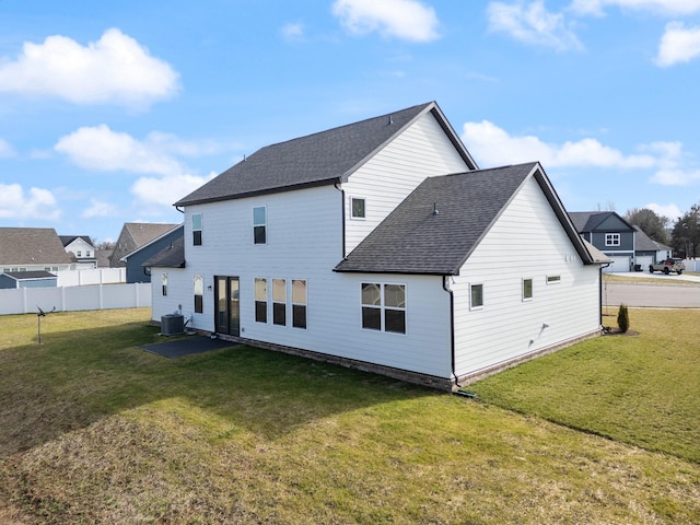 rear view of house with central air condition unit and a lawn