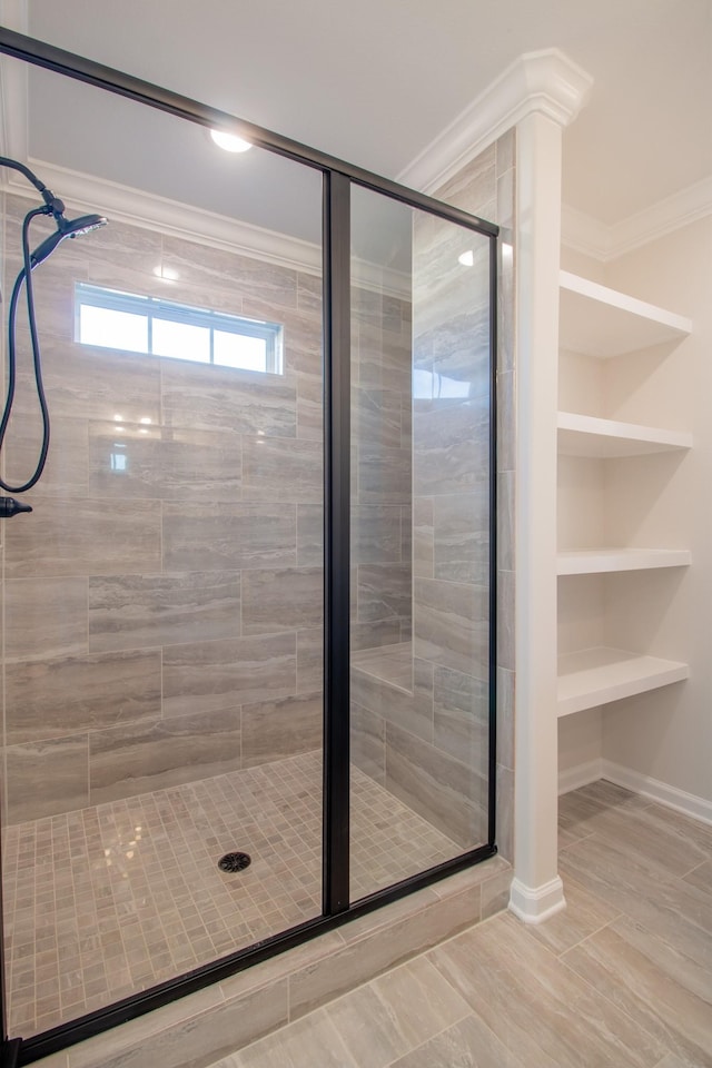 bathroom featuring built in shelves, ornamental molding, and a shower with shower door