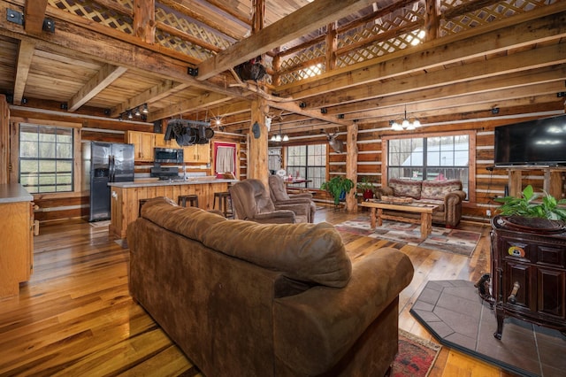 living room featuring plenty of natural light, hardwood / wood-style floors, a notable chandelier, and beam ceiling