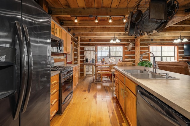 kitchen featuring sink, a wealth of natural light, rustic walls, and black appliances