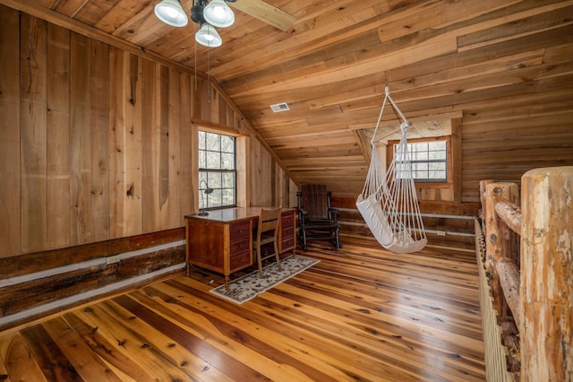 additional living space featuring hardwood / wood-style flooring, vaulted ceiling, a healthy amount of sunlight, and wood walls