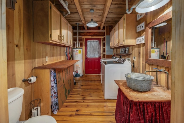 washroom featuring gas water heater, wood walls, light hardwood / wood-style floors, wooden ceiling, and washer and clothes dryer