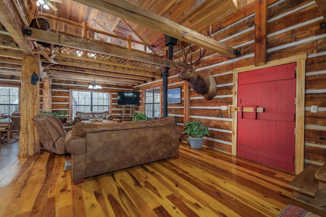 living room with high vaulted ceiling, rustic walls, hardwood / wood-style flooring, wooden ceiling, and beam ceiling