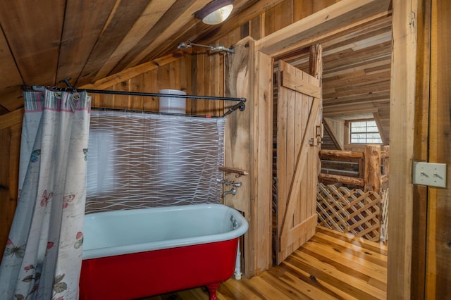 bathroom featuring vaulted ceiling, wood walls, a tub to relax in, hardwood / wood-style flooring, and wood ceiling