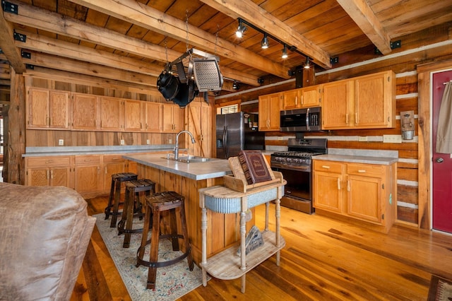 kitchen with sink, wood ceiling, a center island with sink, a kitchen breakfast bar, and stainless steel appliances