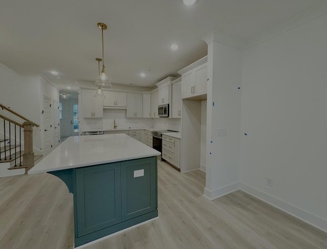 kitchen with pendant lighting, stainless steel appliances, a center island, white cabinets, and light wood-type flooring