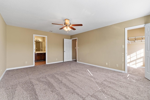 unfurnished bedroom featuring ensuite bathroom, carpet flooring, ceiling fan, and a spacious closet