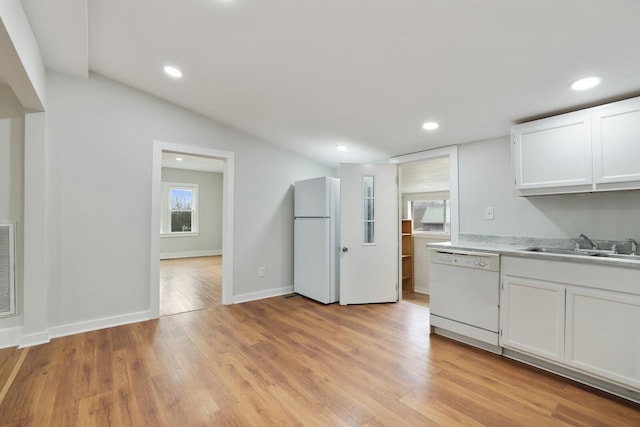 kitchen with lofted ceiling, sink, white cabinetry, white appliances, and light hardwood / wood-style floors