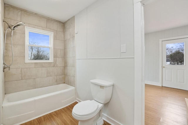 bathroom featuring hardwood / wood-style flooring, tiled shower / bath, a healthy amount of sunlight, and toilet