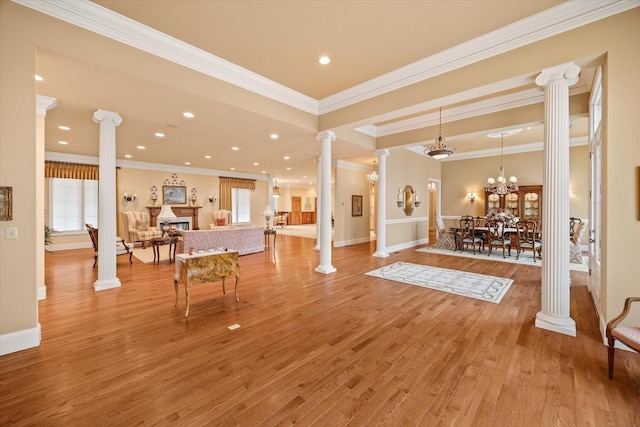 interior space featuring hardwood / wood-style flooring, crown molding, a chandelier, and decorative columns