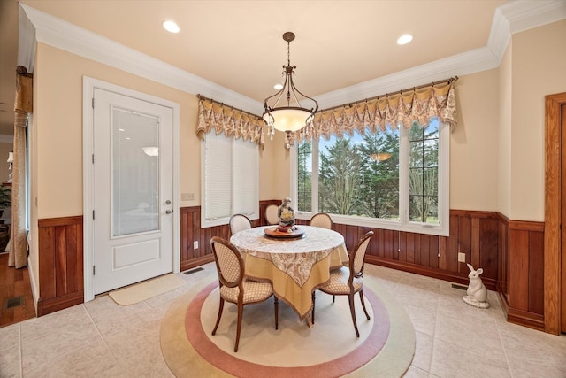 dining area featuring light tile patterned floors, wooden walls, and ornamental molding