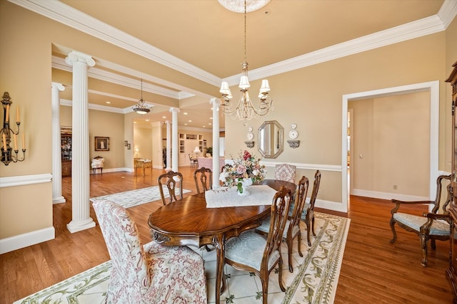 dining area featuring ornate columns, ornamental molding, hardwood / wood-style floors, and an inviting chandelier