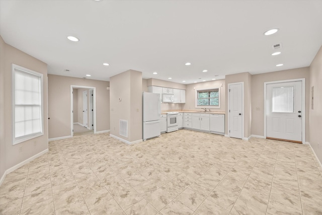 kitchen featuring sink, white cabinets, and white appliances