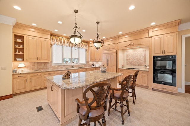 kitchen featuring light stone countertops, black appliances, a kitchen island, decorative light fixtures, and light brown cabinets