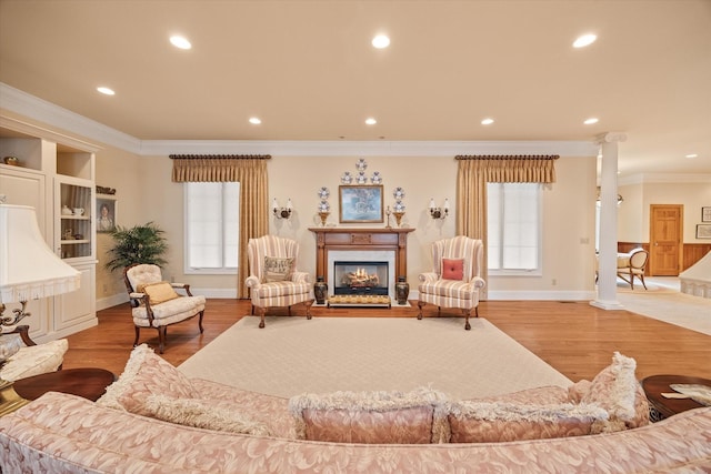 living room featuring decorative columns, ornamental molding, and hardwood / wood-style flooring