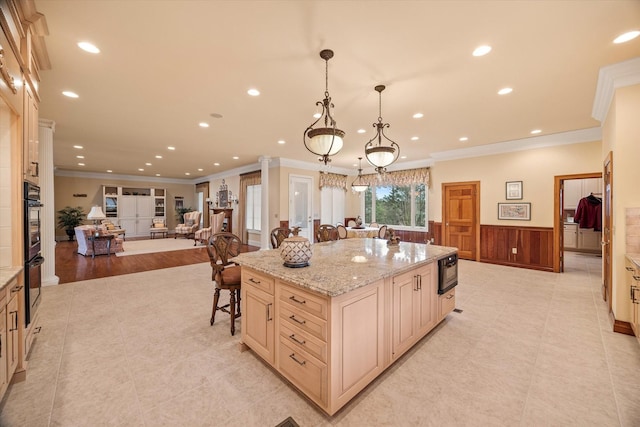 kitchen with black oven, decorative light fixtures, a breakfast bar area, a large island, and light stone countertops