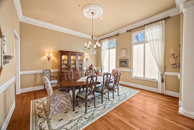 dining space featuring crown molding, ornate columns, hardwood / wood-style floors, and a notable chandelier