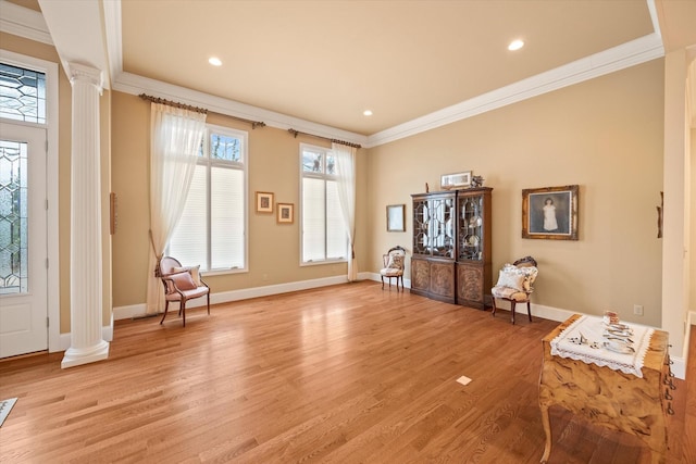 foyer entrance featuring crown molding, light hardwood / wood-style floors, and ornate columns