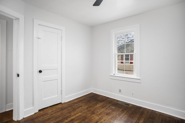 spare room with dark wood-style floors, visible vents, baseboards, and a ceiling fan