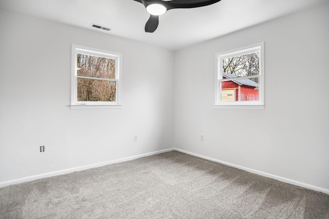 carpeted empty room with baseboards, visible vents, and a ceiling fan