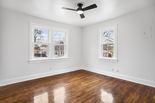 unfurnished room with a ceiling fan, visible vents, baseboards, and dark wood-style flooring