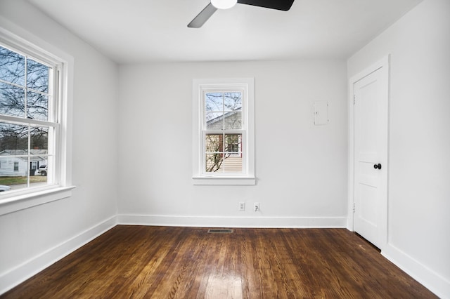 spare room with dark wood-style floors, visible vents, baseboards, and a ceiling fan