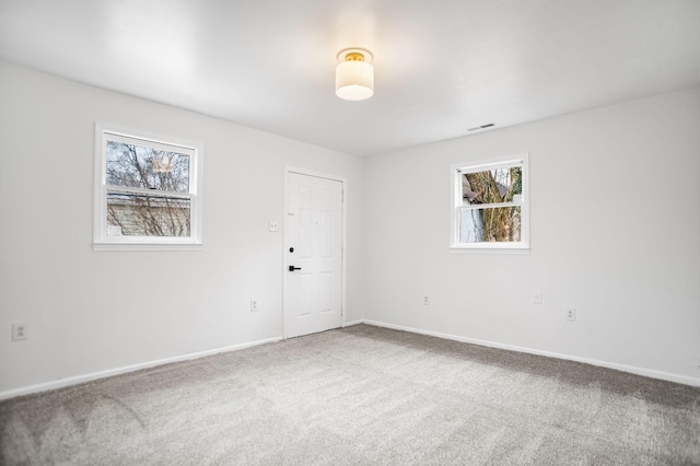 carpeted empty room featuring baseboards and visible vents