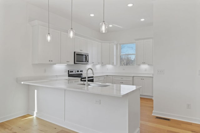 kitchen featuring white cabinetry, stainless steel appliances, decorative light fixtures, and kitchen peninsula