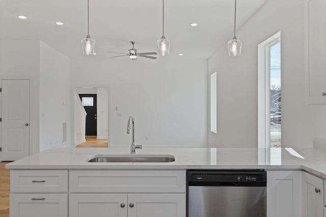 kitchen featuring decorative light fixtures, dishwasher, sink, and white cabinets