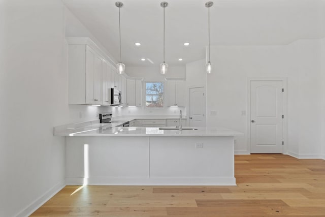 kitchen featuring sink, kitchen peninsula, white cabinets, and appliances with stainless steel finishes