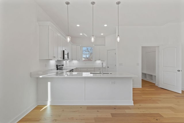 kitchen featuring white cabinetry, sink, kitchen peninsula, and appliances with stainless steel finishes