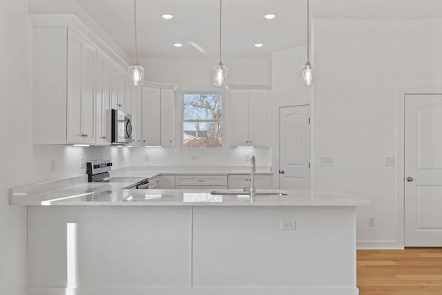 kitchen with white cabinetry, appliances with stainless steel finishes, kitchen peninsula, and sink