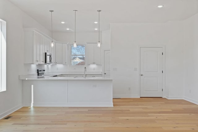 kitchen with sink, white cabinets, hanging light fixtures, kitchen peninsula, and stainless steel appliances