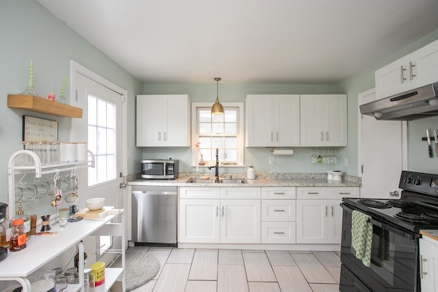 kitchen featuring appliances with stainless steel finishes, decorative light fixtures, sink, white cabinets, and light stone counters