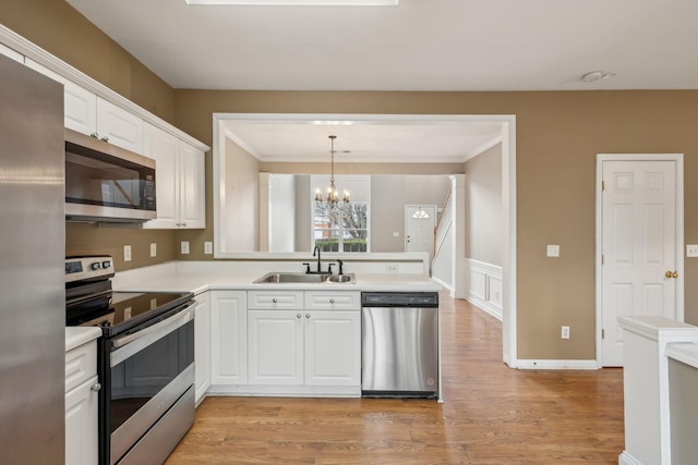 kitchen featuring sink, hanging light fixtures, stainless steel appliances, a notable chandelier, and white cabinets