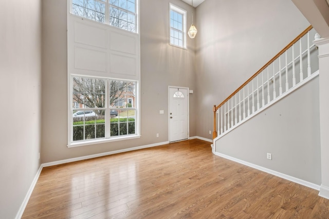 foyer with a wealth of natural light, light hardwood / wood-style floors, and a high ceiling