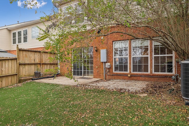 rear view of property with cooling unit, a yard, and a patio area