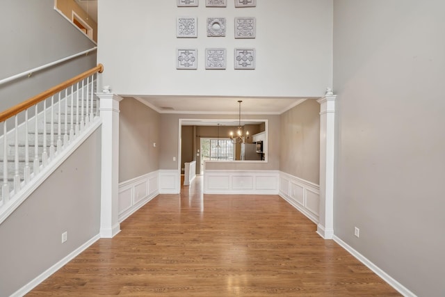 unfurnished living room with hardwood / wood-style flooring, crown molding, and an inviting chandelier