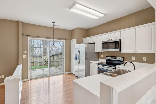 kitchen with sink, appliances with stainless steel finishes, white cabinets, decorative light fixtures, and kitchen peninsula