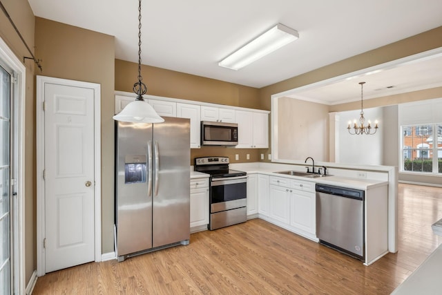 kitchen with sink, stainless steel appliances, light hardwood / wood-style floors, white cabinets, and decorative light fixtures