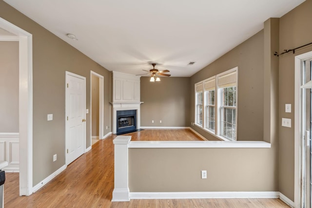 interior space with a large fireplace, ceiling fan, and light wood-type flooring