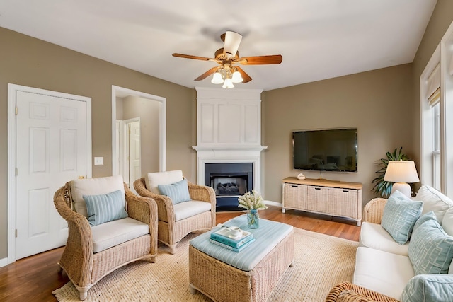 living room with a large fireplace, hardwood / wood-style floors, and ceiling fan