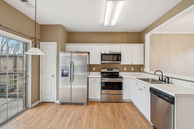 kitchen with sink, white cabinetry, stainless steel appliances, light hardwood / wood-style floors, and decorative light fixtures