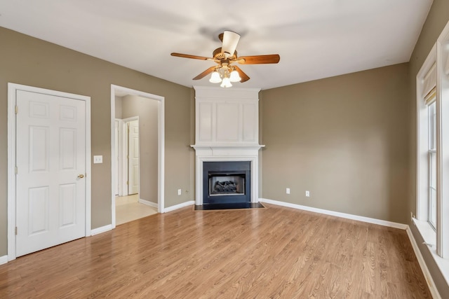 unfurnished living room featuring light hardwood / wood-style flooring, a large fireplace, and ceiling fan