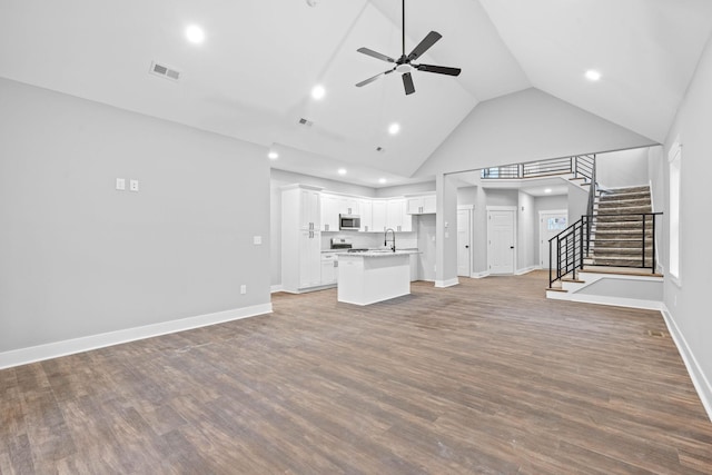 unfurnished living room with high vaulted ceiling, sink, hardwood / wood-style floors, and ceiling fan