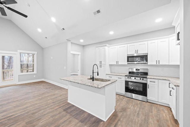 kitchen with sink, white cabinetry, stainless steel appliances, light stone countertops, and an island with sink